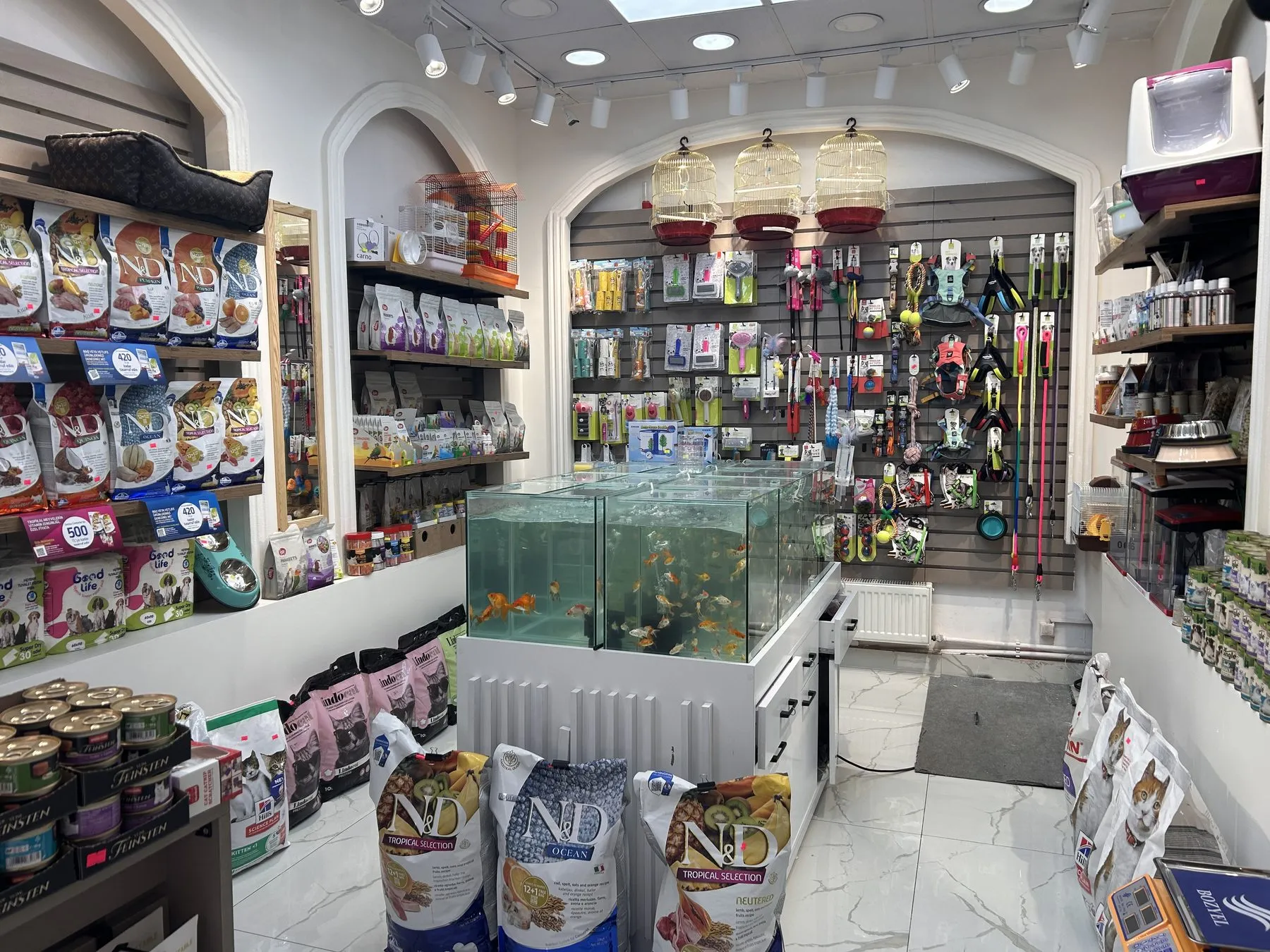 Bahçeli Petshop'ta tasma, oyuncak, kuş kafesi ve mama rafları